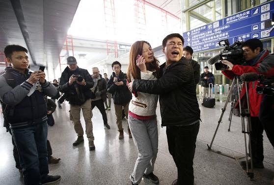 A woman (C), believed to be the relative of a passenger onboard Malaysia Airlines flight MH370, cries as she talks on her mobile phone at the Beijing Capital International Airport in Beijing, March 8. Reuters.