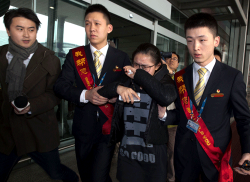 A woman in tears is helped by airport workers to a bus waiting for relatives of the missing Malaysian airliner at the international airport in Beijing, China, Saturday, March 8, 2014. A Malaysia Airlines Boeing 777-200 carrying 239 people lost contact over the South China Sea early Saturday morning on a flight from Kuala Lumpur to Beijing, and international aviation authorities still hadn't located the jetliner several hours later. (AP Photo/Ng Han Guan)