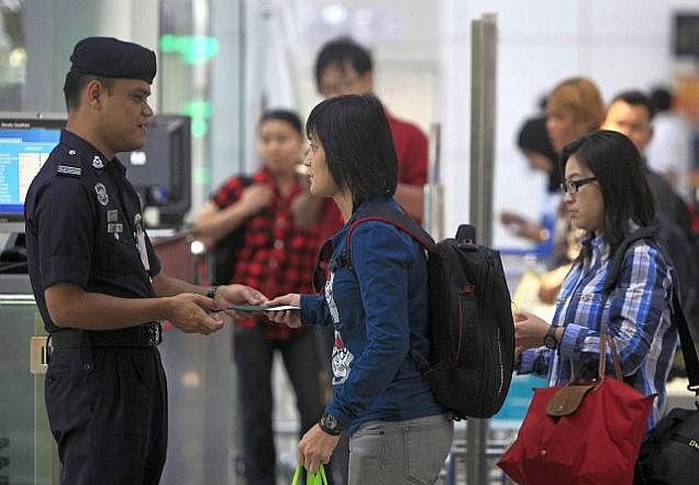 A Malaysian police officer checks passengers' identification documents at Kuala Lumpur International Airport in Sepang, Malaysia on Sunday.