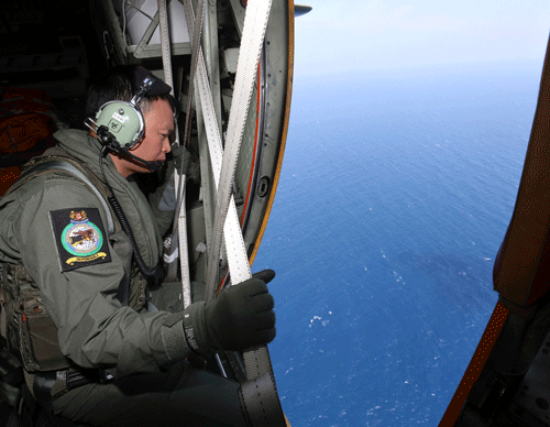 A member of the military personnel looks out of a RSAF C130 transport plane as they search for the missing Malaysia Airlines MH370 plane over the South China Sea. Reuters Image