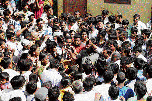 People gather outside Ashwini Public School in Laggere after a Class 2 student was killed in an accident. DH photo