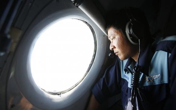 Military officer Nguyen Tran looks out from a Vietnam Air Force AN-26 aircraft during a mission to find the missing Malaysia Airlines flight MH370, off Con Dao island, March 14, 2014. Reuters