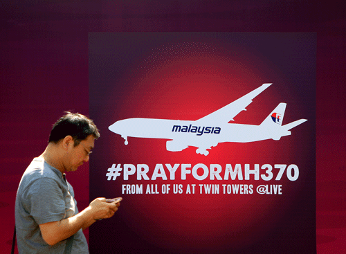 A man walks past a board reading 'Pray for MH370' for passengers aboard a missing Malaysia Airlines plane, in Kuala Lumpur, Malaysia, Saturday, March 15, 2014. Investigators have concluded that one or more people with significant flying experience hijacked the missing Malaysia Airlines jet, switched off communication devices and steered it off-course, a Malaysian government official involved in the investigation said Saturday. (AP Photo)