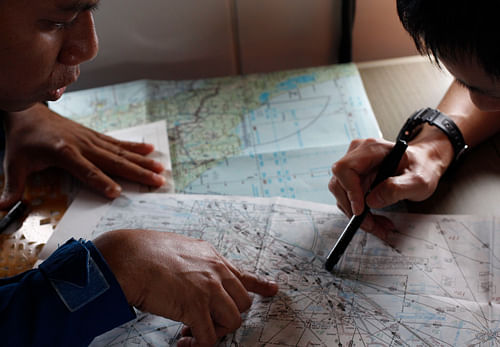 JCG studies a map with a Malaysian Maritime Enforcement Agency pilot in JCG's Gulfstream V Jet aircraft as they search for the missing plane over the South China Sea. Reuters