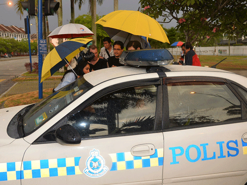 Journalists attempt to get information from Malaysian police officers after they came out of the missing Malaysia Airlines pilot Zaharie Ahmad Shah's house in Shah Alam, outside Kuala Lumpur, Malaysia, Saturday, March 15, 2014. Malaysian police have already said they are looking at the psychological state, the family life and connections of pilot Zaharie, 53, and co-pilot Fariq Abdul Hamid, 27. Both have been described as respectable, community-minded men. The Malaysian jetliner missing for more than a week had its communications deliberately disabled and its last signal came about 7 1/2 hours after takeoff, meaning it could have ended up as far as Kazakhstan or into the southern reaches of the Indian Ocean, Malaysian Prime Minister Najib Razak said Saturday. (AP Photo)