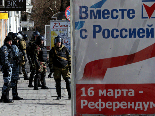 Members of a Crimean self-defence patrol near a referendum poster on a street in Simferopol March 17, 2014. Crimea's Moscow-backed leaders declared a 96-percent vote in favor of quitting Ukraine and annexation by Russia in a referendum Western powers said was illegal and will bring immediate sanctions. Poster reads 'Together with Russia. 16 March - Referendum'. REUTERS