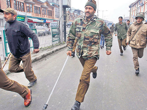 Policemen chase JKLF protesters in Srinagar on Monday. AP