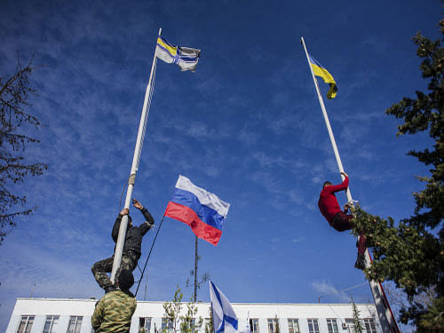 Members of the Crimean pro-Russian self-defense forces climb up to take down a Ukrainian flag and a Ukrainian navy flag, at the Ukrainian navy headquarters in Sevastopol, Crimea. AP Photo