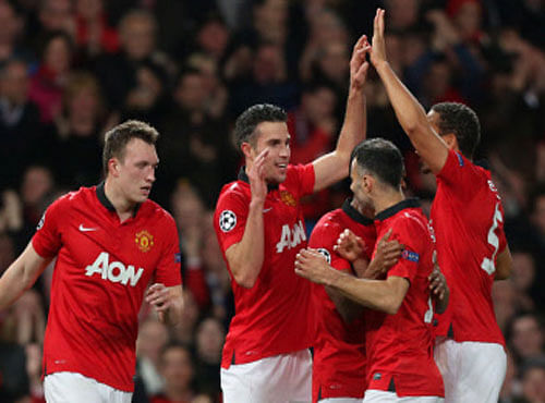 Manchester United's Robin van Persie, celebrates his hatrick and scoring his side's third goal with his teammates during their Champions League last 16 second leg soccer match against Olympiakos at Old Trafford Stadium, Manchester, March 19, 2014. AP Photo