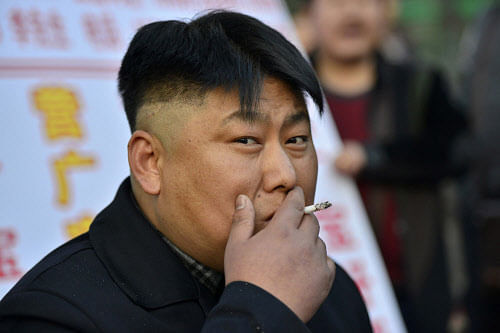 Xia, a 38-year-old lookalike of North Korean leader Kim Jong Un, smokes a cigarette at his barbeque food stall in Shenyang, Liaoning province March 22, 2014. Street vendor Xia and his food stall in northern city Shenyang went viral after pictures of him started to circulate on the Internet and in the media last week, local media reported. Picture taken March 22, 2014. REUTERS