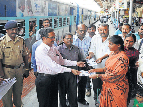Rajkumar Lal, Divisional Railway Manager,South Western Railway(SWR) distributes pamphlets to a passenger as part of cleanliness and voter awareness drive, in Mysore, on Friday.  DH Photo