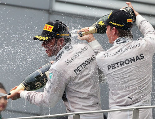 Second placed Mercedes driver Nico Rosberg, right, of Germany sprays champagne on race winner and teammate Lewis Hamilton of Britain on the podium following the Malaysian Formula One Grand Prix at Sepang International Circuit in Sepang, Malaysia, Ap phot