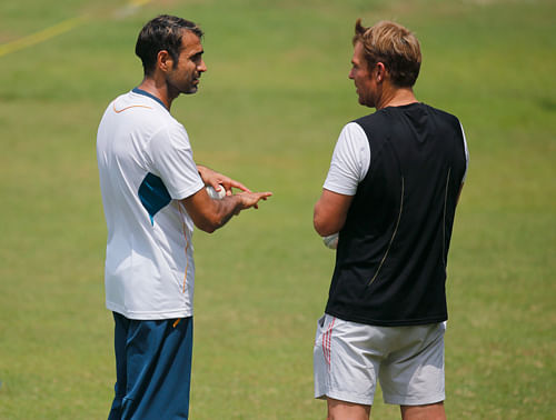 Australian cricket legend Shane Warne, right, gives bowling tips to South Africa's Imran Tahir during a training session ahead of their ICC Twenty20 Cricket World Cup semi-final match against India in Dhaka, Bangladesh, Wednesday, April 2, 2014. (AP Photo/Aijaz Rahi)