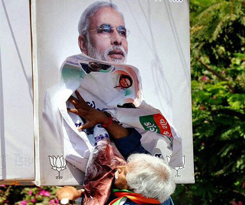 Congress candidate Madhunsudan Mistry removing a poster of Narendra Modi from a street light pole in Vadodara on Thursday. PTI Photo