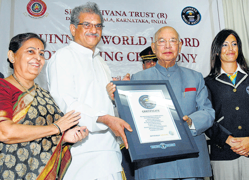 Governor H R Bhardwaj presents a Guinness World Records certificate to chairperson of Shantivana Trust D Veerendra Heggade, at Raj Bhavan on Thursday. Hemavathi, Heggade's wife, and Lucia Senigagliasi, a representative from the Guinness World Records, are seen.  DH Photo