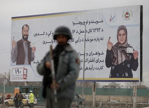 1 OF 7. A policeman stands near a billboard for the presidential election at a checkpoint in Kabul, April 4, 2014, before Saturday's presidential election.