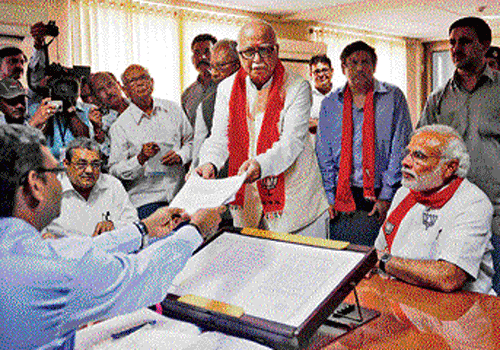 L&#8200;K Advani (C) hands his nomination papers to an election officer as BJP prime ministerial candidate Narendra Modi  looks on at Gandhinagar on Saturday. REUTERS