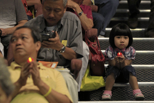 A girl holding a LED candle as she joins a mass prayer for the missing Malaysia Airlines Flight MH370, in Kuala Lumpur, Malaysia, Sunday, April 6, 2014, AP photo