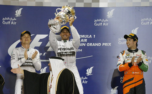 Mercedes driver Lewis Hamilton of Britain, winner, center, holds up his trophy after winning the Bahrain Formula One Grand Prix as second placed Mercedes driver Nico Rosberg of Germany, left, and third placed Force India driver Sergio Perez of Mexico, right, clapping as they stand on the podium after at the Formula One Bahrain International Circuit in Sakhir, Bahrain, Sunday, April 6, 2014. AP Photo
