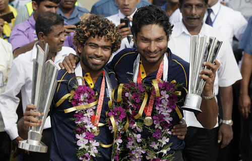 Sri Lanka's T20 cricket World Cup winning team's captain Lasith Malinga, left, and teammate Kumar Sangakkara pose with their trophies upon the arrival from Dhaka in Colombo, Sri Lanka, Tuesday, April. 8, 2014. Sri Lanka won the title Sunday defeating India by six wickets. AP Photo