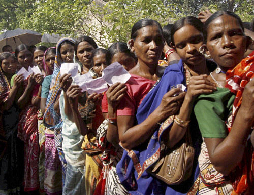 Women belonging to the Kandha tribe wait to cast their votes outside a polling station at a village in Kandhamal district on Thursday during third phase of polling for Lok Sabha elections. PTI Photo