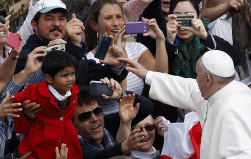 Pope Francis greets faithful at the end of the Palm Sunday mass in St. Peter's square at the Vatican, Sunday, April 13, 2014. Tens of thousands of Romans, tourists and pilgrims have joined Pope Francis in a solemn Palm Sunday service in St. Peter's Square. Palm Sunday begins Holy Week, which culminates next Sunday on Easter. Francis used a pastoral staff made of wood carved by Italian prison inmates, who donated it to him. The pope is determined to put people on the margins of life at the center of the Roman Catholic church's attention. AP photo
