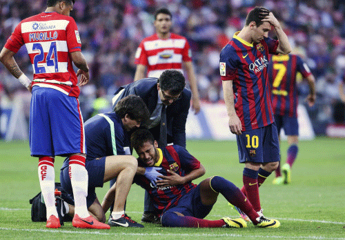 Barcelona's Neymar is helped by the medical staff next to Lionel Messi (R) during their Spanish First Division soccer match against Granada at Nuevo Los Carmenes stadium in Granada. Reuters photo