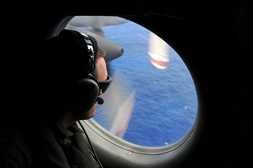 In this photo taken from the Royal New Zealand Air force (RNZAF) P-3K2-Orion aircraft, a spotter looks out of a window in search of debris from the missing Malaysia Airlines Flight 370, in the Indian Ocean off the coast of western Australia on Sunday, April 13, 2014. The hunt for the missing Malaysian airliner continued to focus Monday on a search for weakening radio signals from deep beneath the waves despite mounting evidence that the batteries in the plane's all-important black boxes may finally have died.