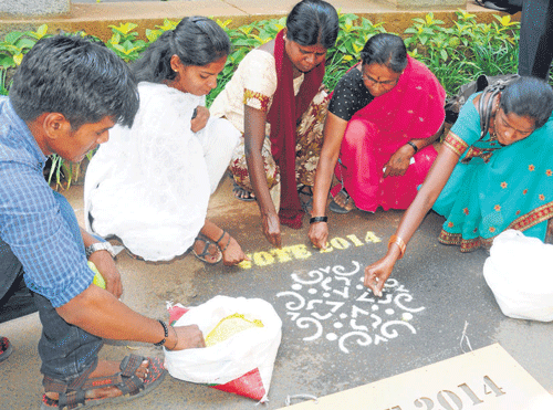 People drawing rangolis with election messages to attract voters.  DH photo