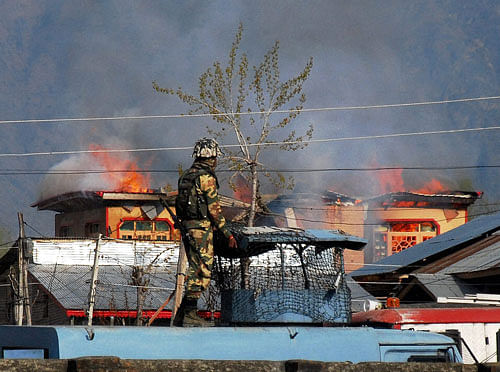A security person looks at the burning house during an encounter with Lashkar-e-Toiba (LeT) militants at Ahmed Nagar Soura, Srinagar on Monday. PTI Photo