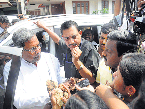 Chief Minister Siddaramaiah's neighbours (carrying stones in their hands) complain to him about the alleged high-handedness of his personal secretary, outside his private residence in Mysore on Tuesday.  DH Photo