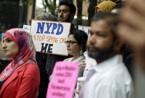 In this Aug. 28, 2014, file photo, a group of people hold signs protesting the New York Police Department's program of infiltrating and informing on Muslim communities during a rally near police headquarters in New York. On Tuesday, April 15, 2014, the NYPD confirmed it disbanded the special intelligence unit that monitored Muslim communities in New York and New Jersey. AP Photo