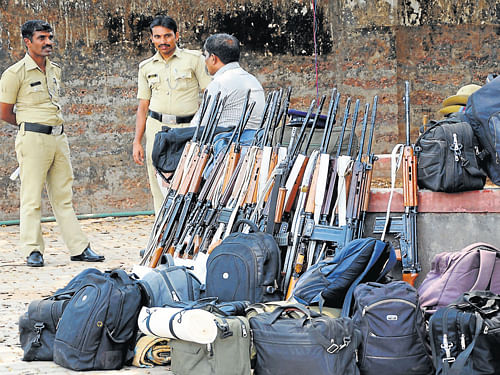 Two police personnel guard weapons before leaving for their destination to take part in poll duty, in Mangalore on Wednesday. DH Photo