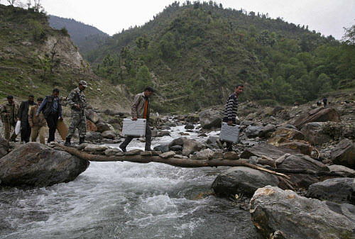 on duty: Members of the election staff carry electronic voting machines (EVM) cross a water channel on their way to polling stations ahead of the fifth phase of the general elections in Assar, north of Jammu, on Wednesday. REUTERS
