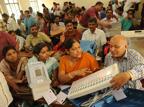 Polling officials checking the EVMs and newly introduced Voter-verified paper audit trail (VVPAT) machine which shows voting details, before leaving for their deputed polling station, at RPC Layout Government College in Bangalore on Wednesday. DH photo