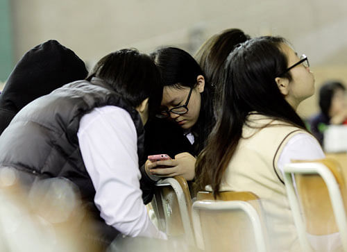 Students check a mobile phone for the latest news on the ferry that sank Wednesday, which was carrying 475 people aboard, including 325 students, at an auditorium in Danwon High School in Ansan, South Korea, Thursday, April 17, 2014. Strong currents, rain and bad visibility hampered an increasingly anxious search Thursday for 287 passengers, many thought to be high school students, still missing more than a day after their ferry flipped onto its side and sank in cold waters off the southern coast of South Korea. AP Photo