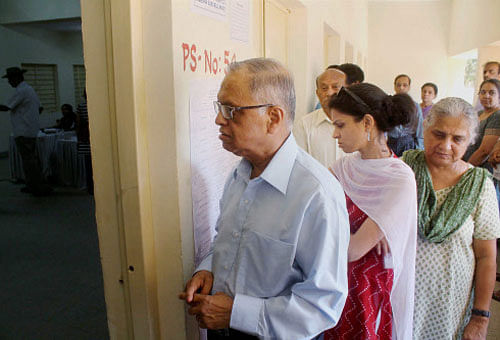 Infosys Executive Chairman N R Narayana Murthy with daughter Akshata and wife Sudha Murthy standing in a queue to cast their votes for Lok Sabha elections at a polling booth in Jayanagara in Bengaluru on Thursday. PTI Photo