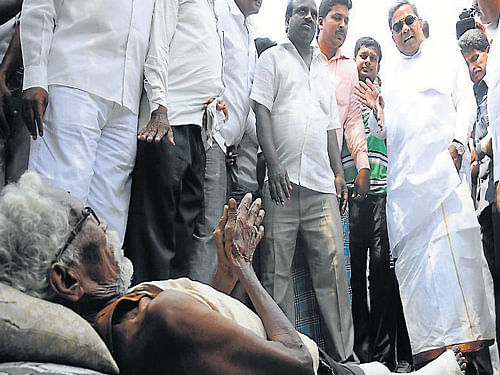 Chief Minister Siddaramaiah interacts with an old man with an injured leg near Siddarameshwara temple in Siddaramanahundi, in Mysore on Thursday. DH Photo