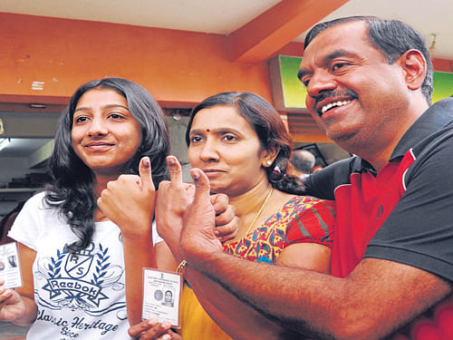 V Balakrishnan, the AAP candidate for  Bangalore Central constituency, shows his ink-marked  finger along with his wife and daughter at a polling booth in  Basaveshwaranagar on Thursday. DH Photo