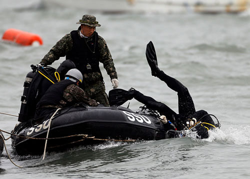 A member from the South Korean Navy's SSU (Ship Salvage Unit) dives into the sea near the sunken passenger ship Sewol during a rescue operation in the sea off Jindo April 19, 2014. Divers searching for survivors of the capsized South Korean ferry saw three bodies floating through a window of a passenger cabin on Saturday but were unable to retrieve them, the coastguard said, hours after the ship's captain was arrested. REUTERS