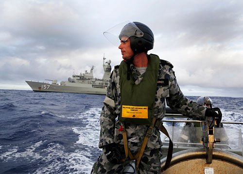 Standing in a rigid hull inflatable boat launched from HMAS Perth, Leading Seaman, Boatswain's Mate, William Sharkey searches for possible debris in the southern Indian Ocean during the continuing search for the missing Malaysian Airlines flight MH370. Reuters