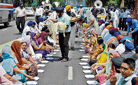 Sikhs have a 'langar' during protests against Congress leaders over the 1984 anti-Sikh riots outside AICC headquarters in New Delhi on Monday. PTI