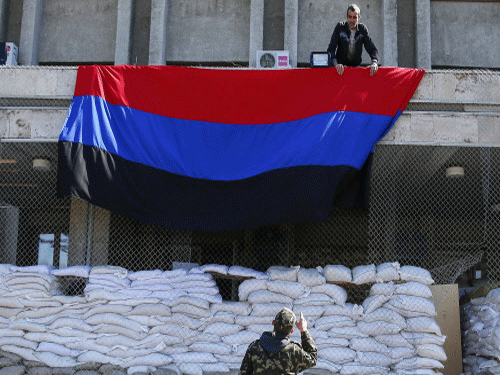 Pro-Russian activists hang a giant flag of 'Donetsk Republic' at the mayor's office in Slaviansk on April 21. Russia will respond if its interests are attacked in Ukraine, as they were in South Ossetia in 2008 which led to war with Georgia, Foreign Minister Sergei Lavrov said today. Reuters Photo