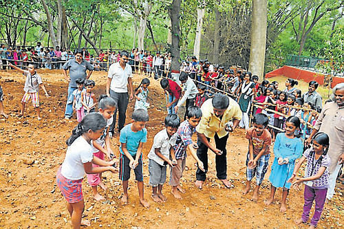 Children are seen sowing sesame seeds, as part of the Chinnara Mela, Rangayana premises, in Mysore, on Wednesday. DH Photo