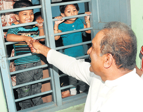 Home Minister K J George greets children at a play home at the police quarters in Bangalore on Wednesday. DH photo