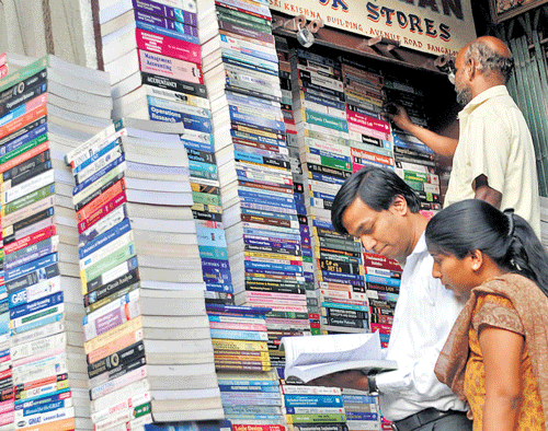 Reading books may be a waning hobby. But avid readers will always look to lay their hands on treasured works.  Enthusiasts surf a book at a shop on the occasion of World Book Day in the City on Wednesday. DH photo