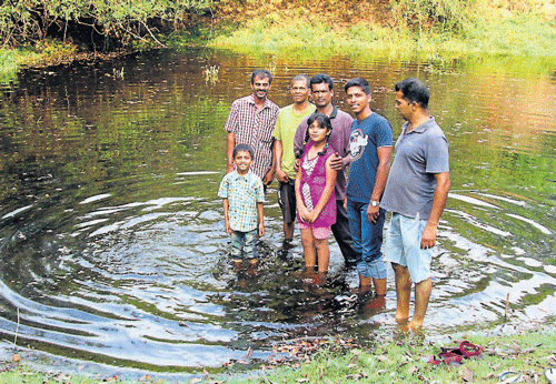 A few villagers stand in the knee-deep water in the pond adjacent to the house of Vamana Naika at Baiderabettu near Parkala. It had gone dry in December. DH photo