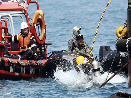 A diver jumps into the sea to look for people believed to have been trapped in the sunken Sewol ferry. The head of the operation to retrieve bodies from the ferry admitted today he had 'no idea' when it would be over, as furious relatives accused recovery teams of dragging their feet. AP Photo