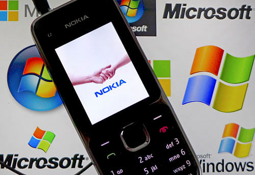 A Nokia mobile phone lies on a tablet computer showing logos of Microsoft, in this illustration file picture taken in Frankfurt, November 18, 2013. Nokia on Friday said the sale of its once-dominant handset business to Microsoft has been closed after the companies agreed to leave two factories in India and Korea out of the deal. REUTERS