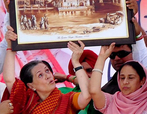 Congress president Sonia Gandhi shows a portrait presented to her during an election rally in Barnala on Saturday. PTI